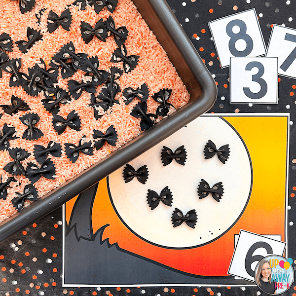 Orange rice sensory bin with black died pasta bats and counting activity